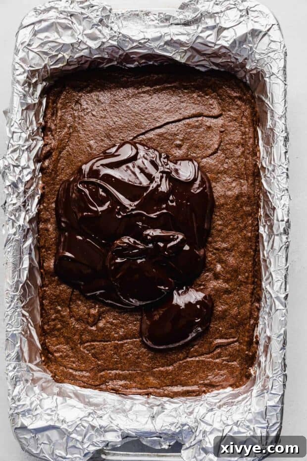 Cosmic Brownie Magic 12 A pile of dark glossy ganache spread evenly atop a pan of baked Cosmic Brownies.