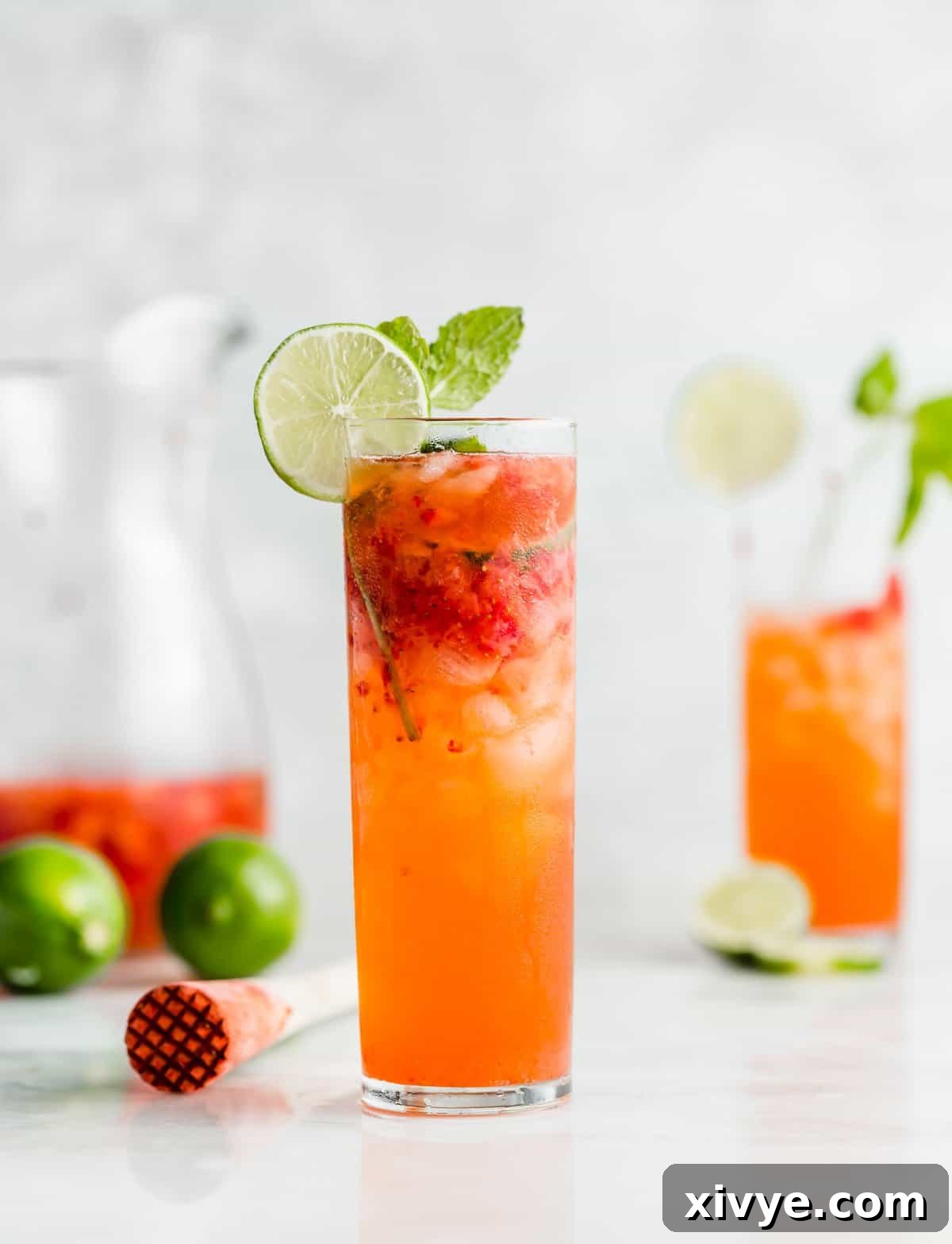 Ruby Red Refresher 2 A tall mojito glass filled with a Strawberry Mocktail and ice with a lime wedge on the rim.