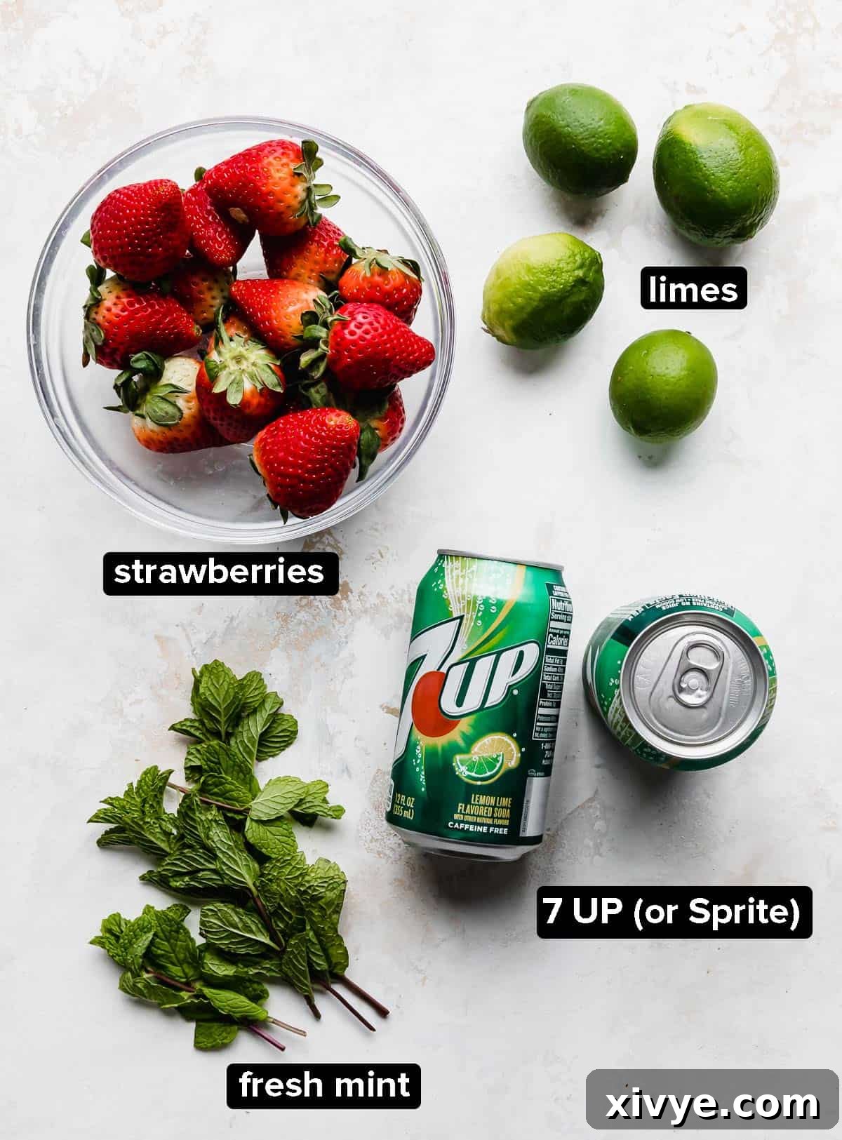 Ruby Red Refresher 3 Strawberry Mocktail ingredients on a white background: limes, strawberries, mint, and Sprite or 7 UP.