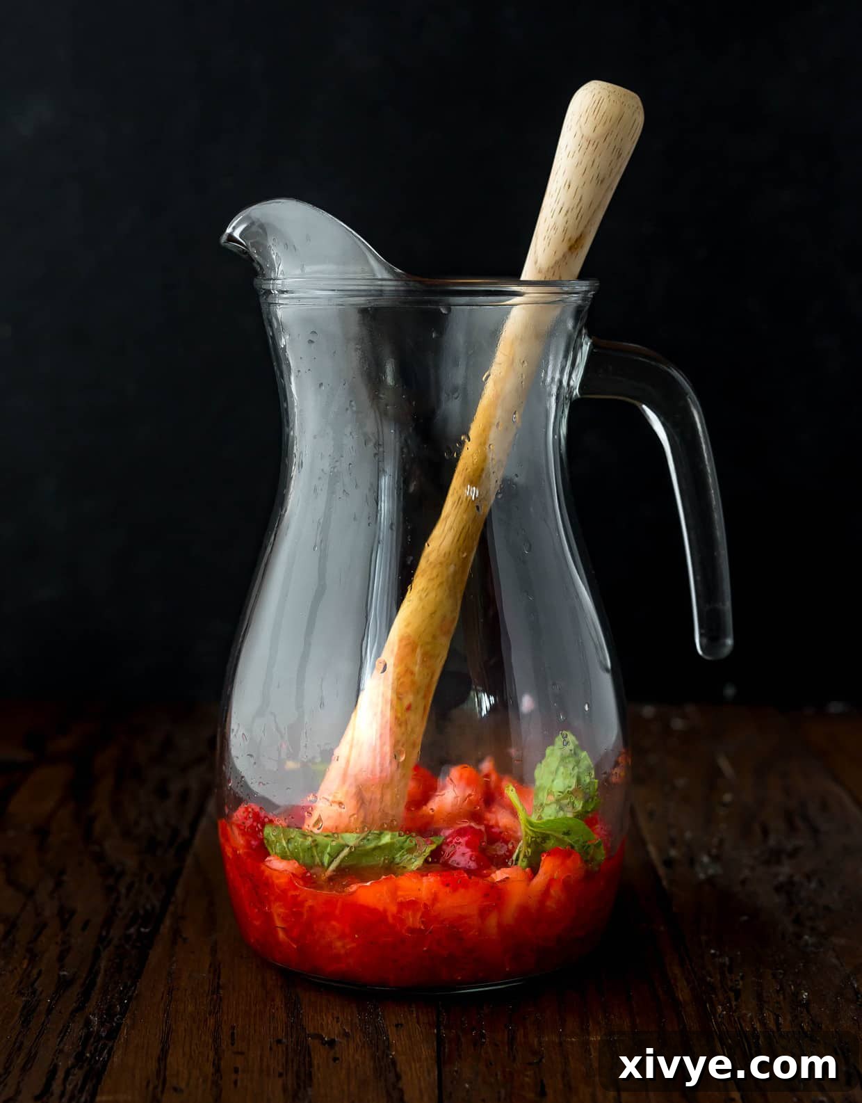 Ruby Red Refresher 4 Glass pitcher with strawberries and mint leaves.