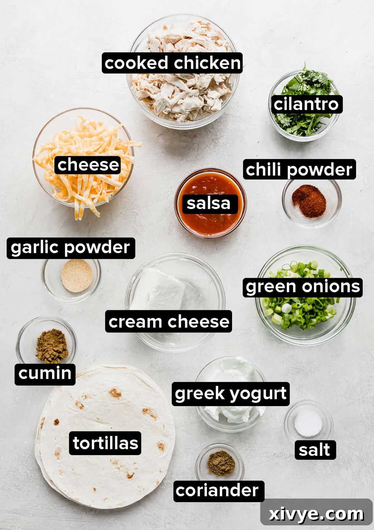 Ingredients used to make baked chicken taquitos, in glass bowls on a white background, clearly organized.