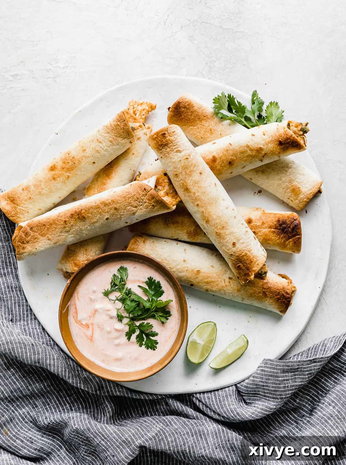 Baked Chicken Taquitos on a white plate against a white background, ready to be served.