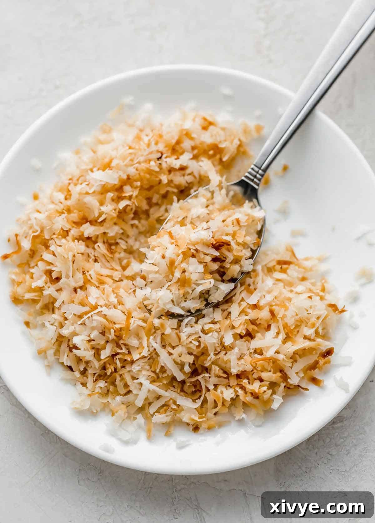 Golden toasted coconut artfully arranged on a clean white plate, showcasing the results of microwave toasting.