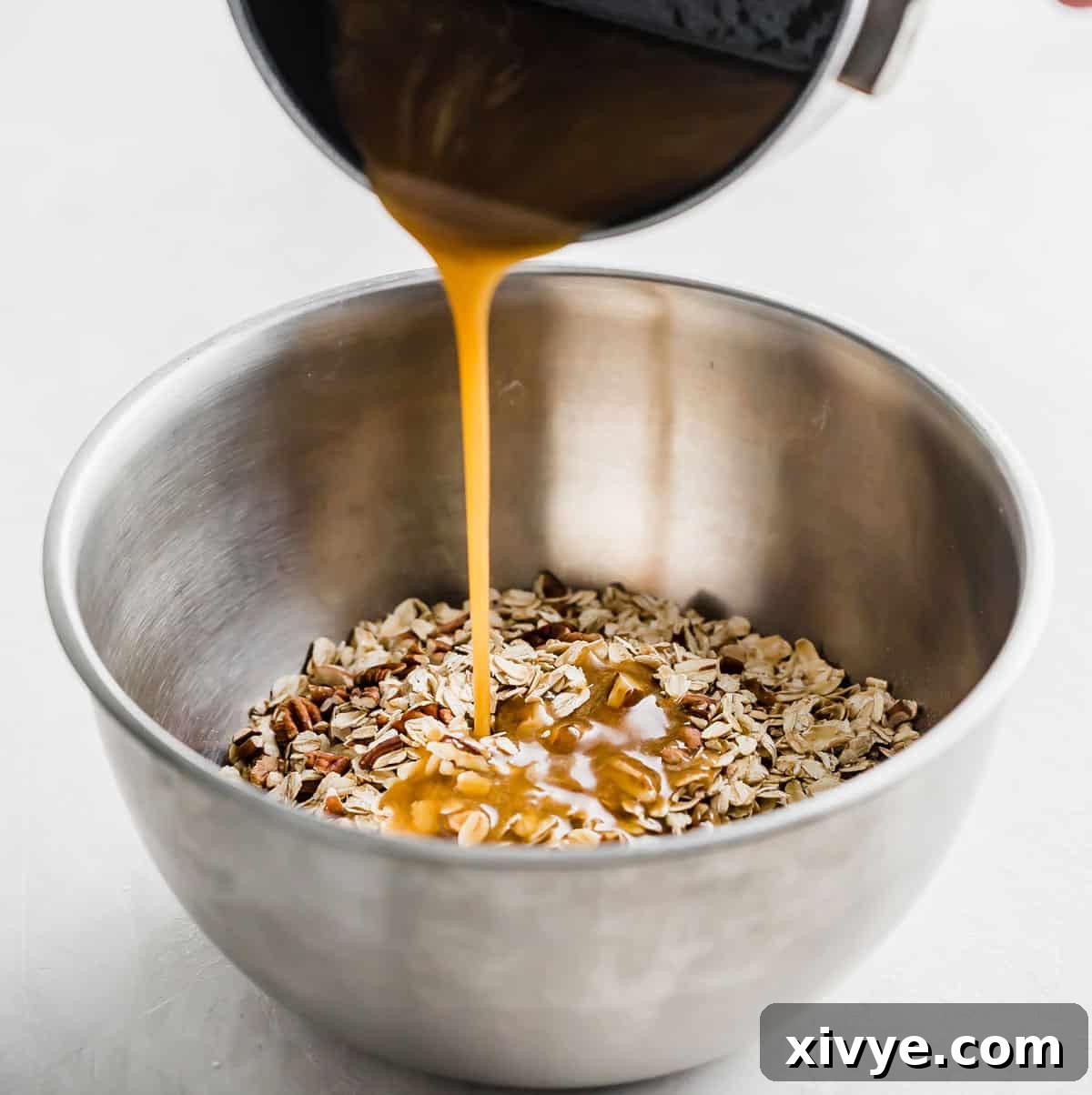 Wholesome Oat & Raisin Granola Bars 5 A brown liquid being poured from a small pot into a metal bowl filled with Oatmeal Raisin Granola Bar mixture.