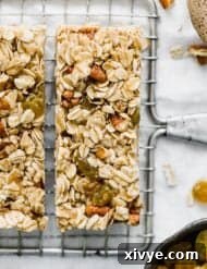 Wholesome Oat & Raisin Granola Bars 11 Homemade granola bars with oatmeal and raisins and nuts sliced into bars on a wire rack, with golden raisins scattered around.