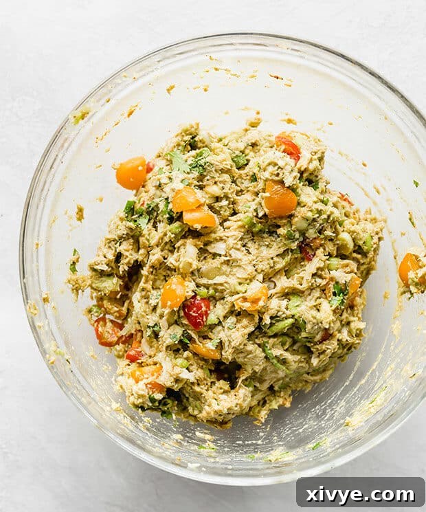 Creamy Avocado Chicken Wraps 6 A large bowl filled with the colorful avocado chicken mixture, showing chicken, avocado, tomatoes, and herbs.