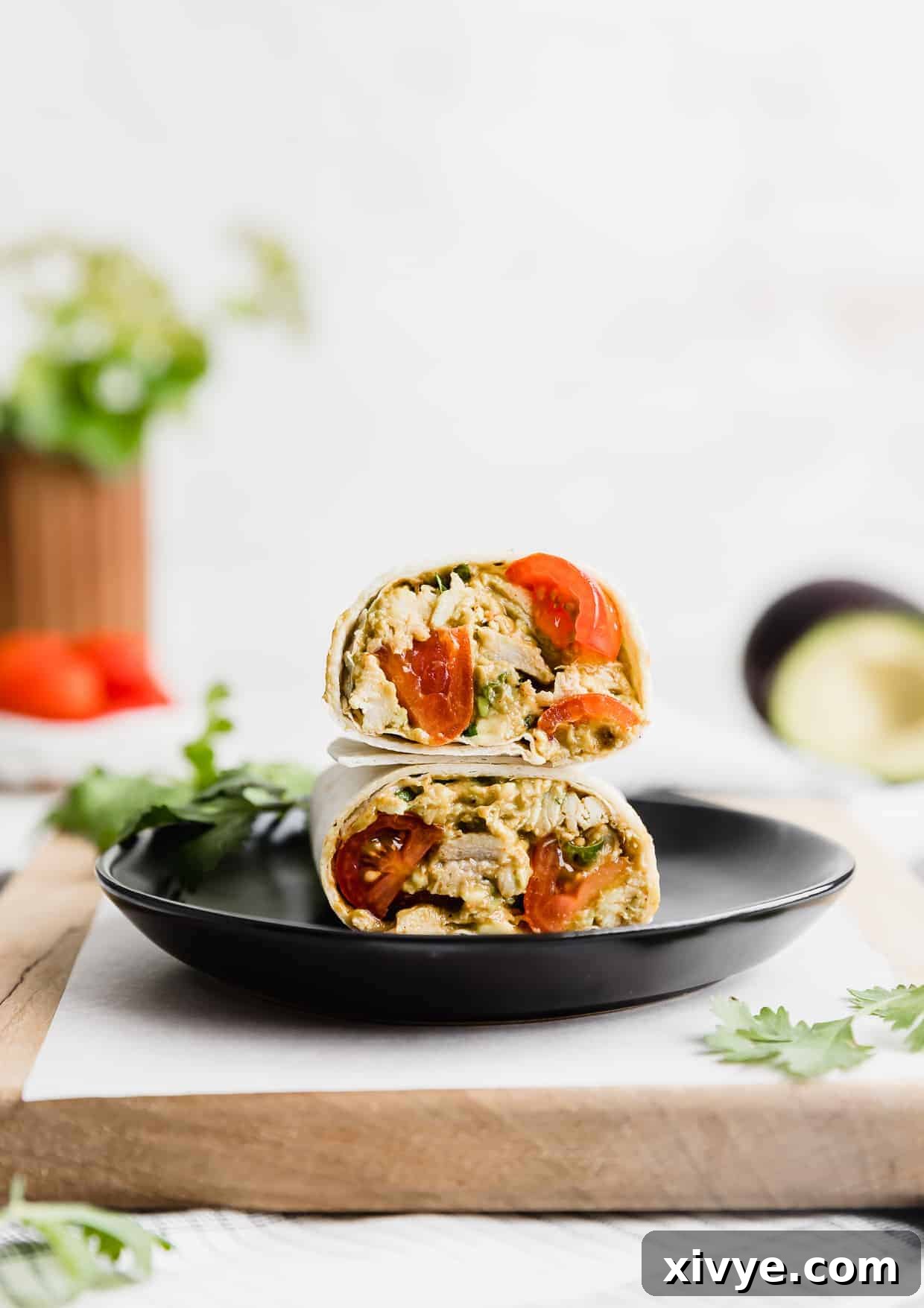 Creamy Avocado Chicken Wraps 9 Several avocado chicken wraps arranged neatly on a black serving plate, ready to be enjoyed.