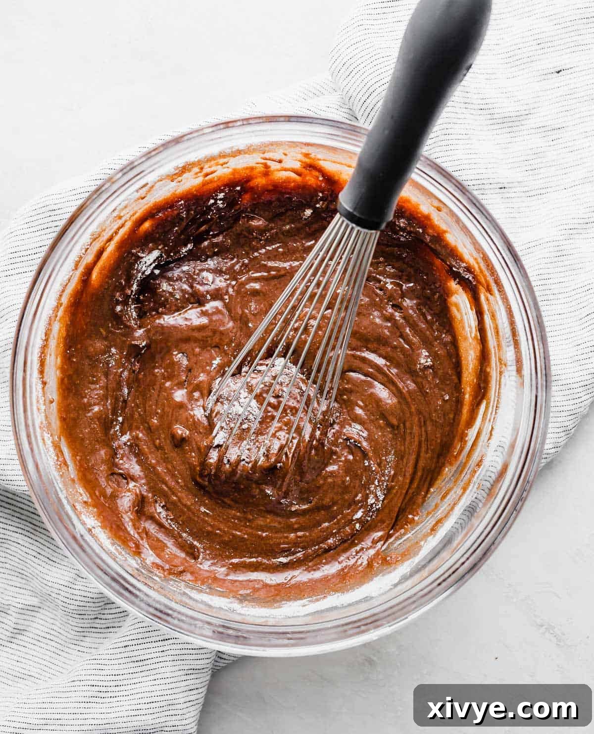 German Chocolate Brownie batter in a glass bowl on a white background.