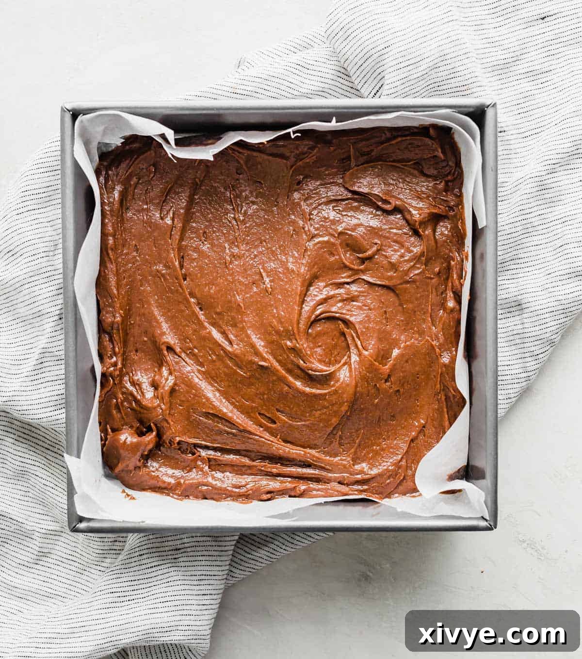 A square pan filled with brown brownie batter.