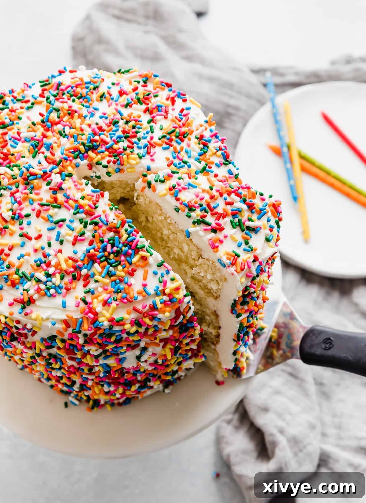 A vibrant sprinkle smash cake recipe with a perfectly cut slice being carefully lifted out, revealing its moist interior.