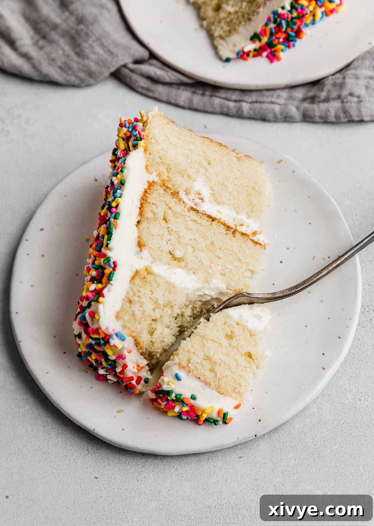 A perfect slice of a multi-colored sprinkle smash cake, presented beautifully on a pristine white plate, showcasing its delightful layers.