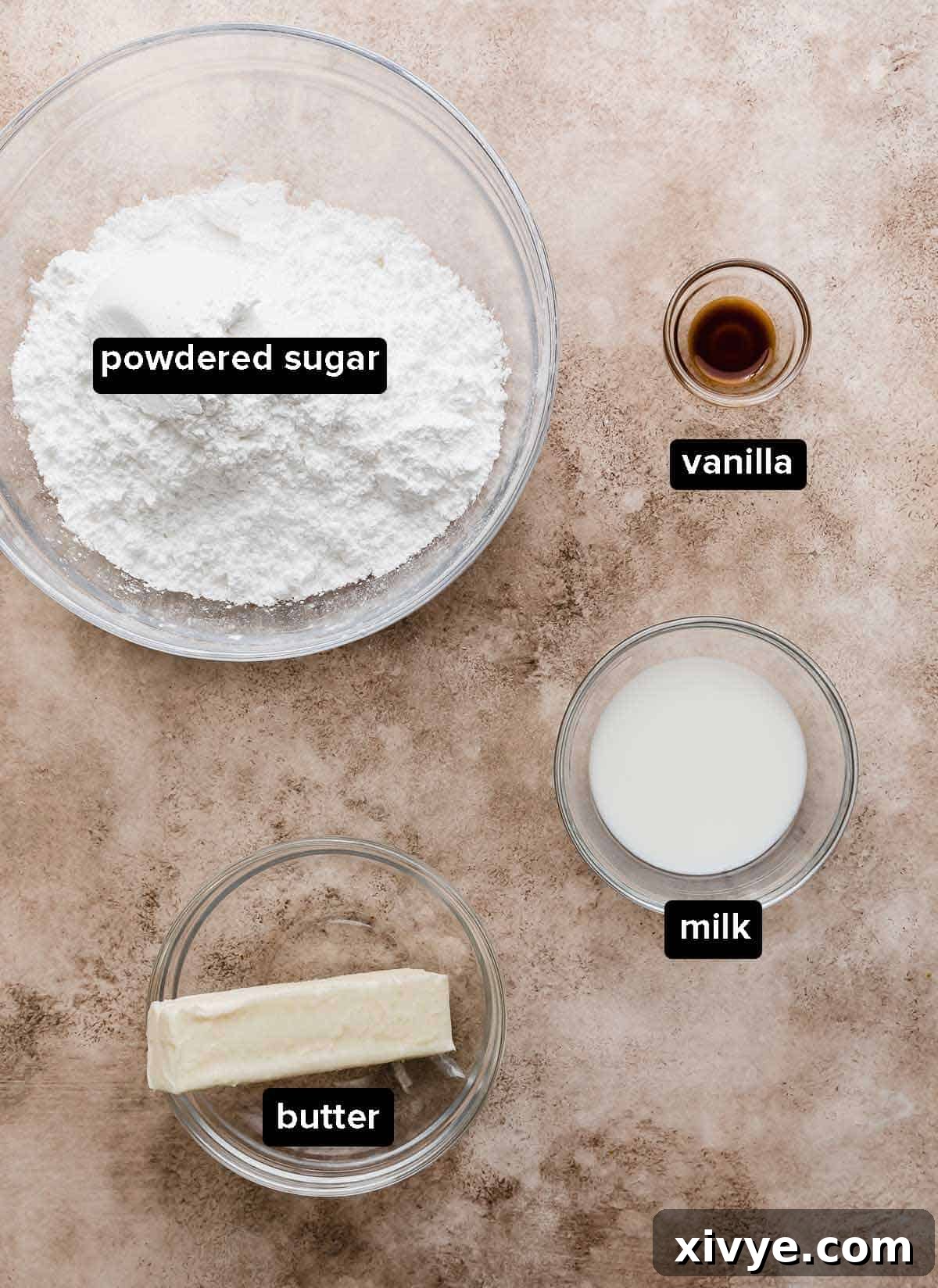 Cinnamon roll frosting ingredients: powdered sugar, vanilla, milk, and butter on a light brown background.