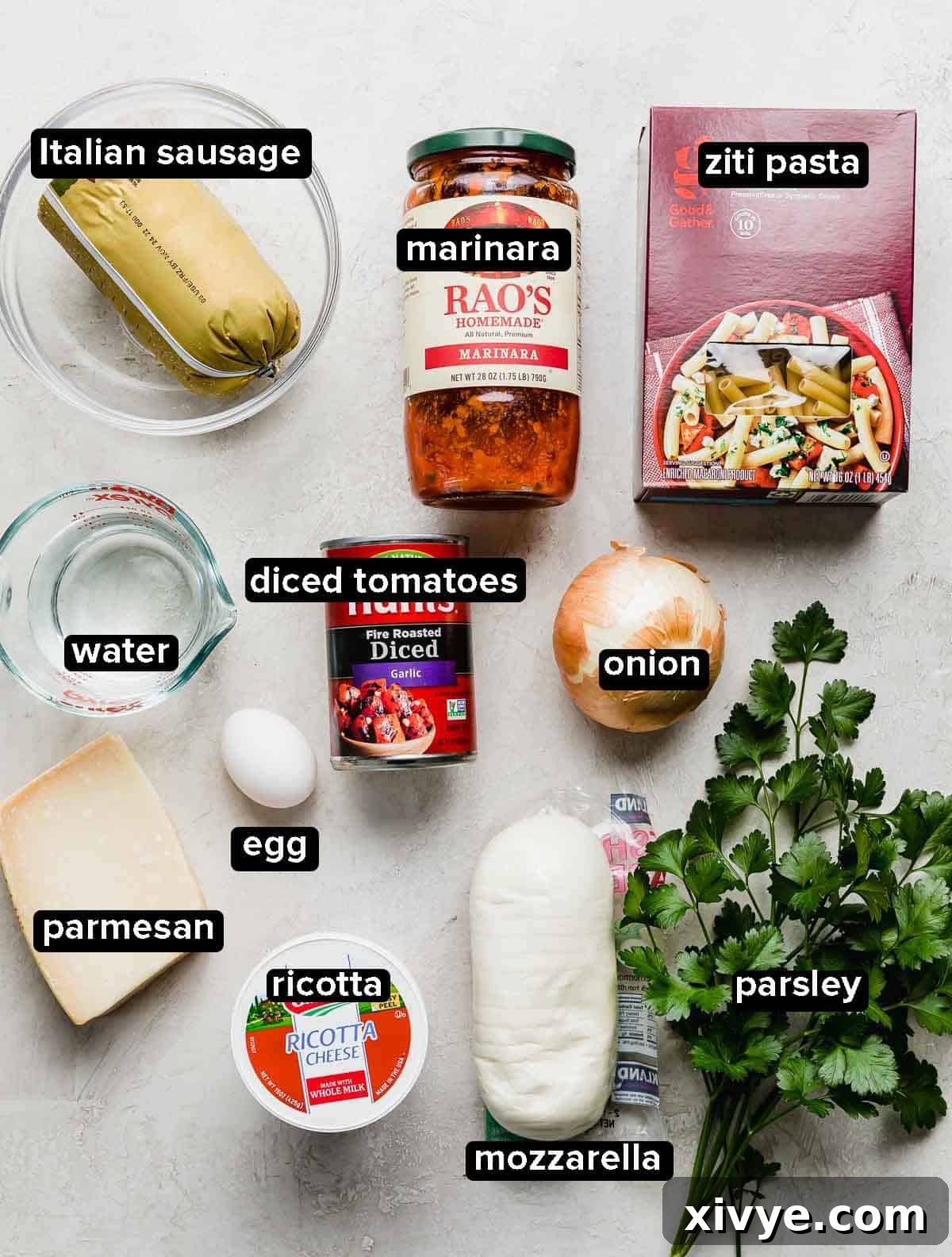 Comforting Sausage Ziti Bake 3 Easy Baked Ziti Recipe ingredients portioned into glass bowls on a white background, including sausage, diced onions, marinara, fire roasted tomatoes, ziti, ricotta, and various cheeses.