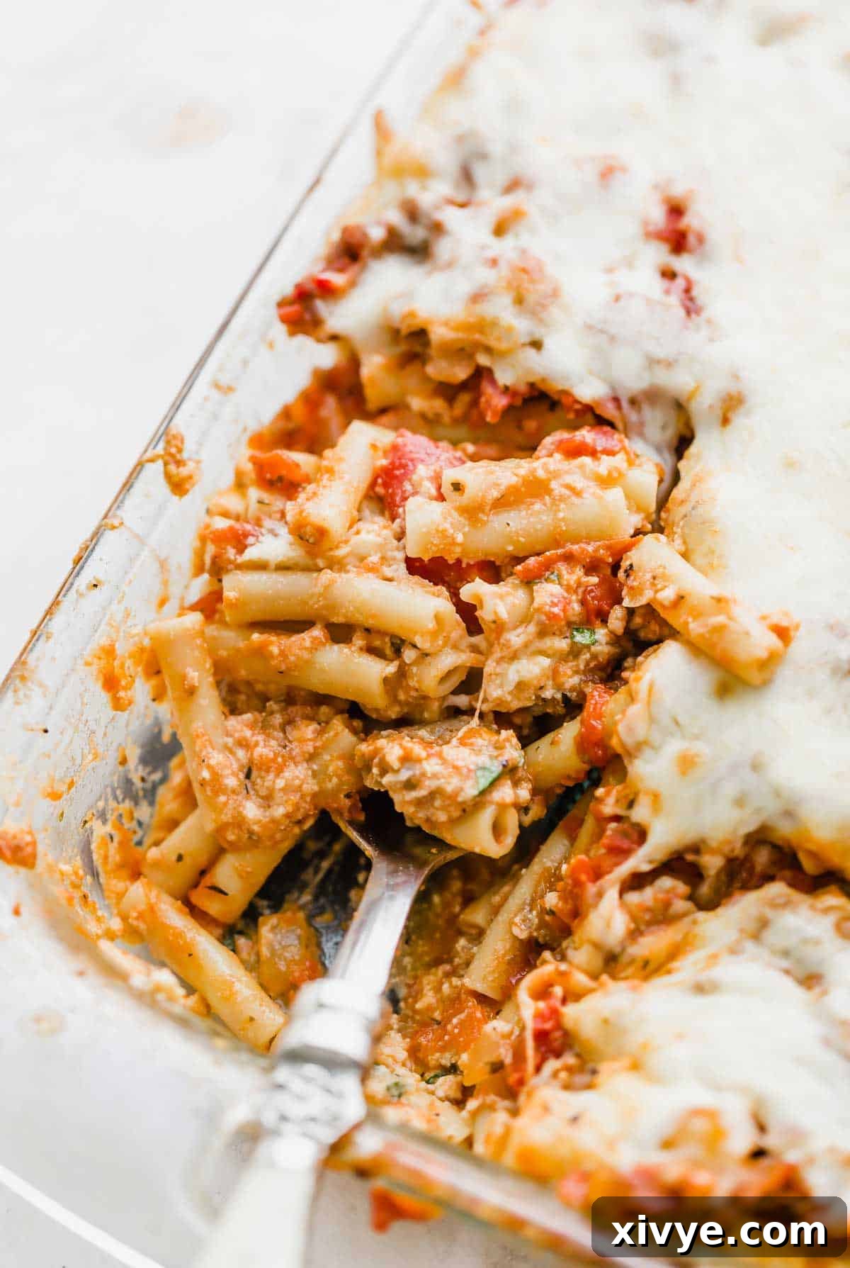 Comforting Sausage Ziti Bake 7 Close up image of baked ziti with ricotta cheese, in a glass pan, showing the rich, cheesy layers.