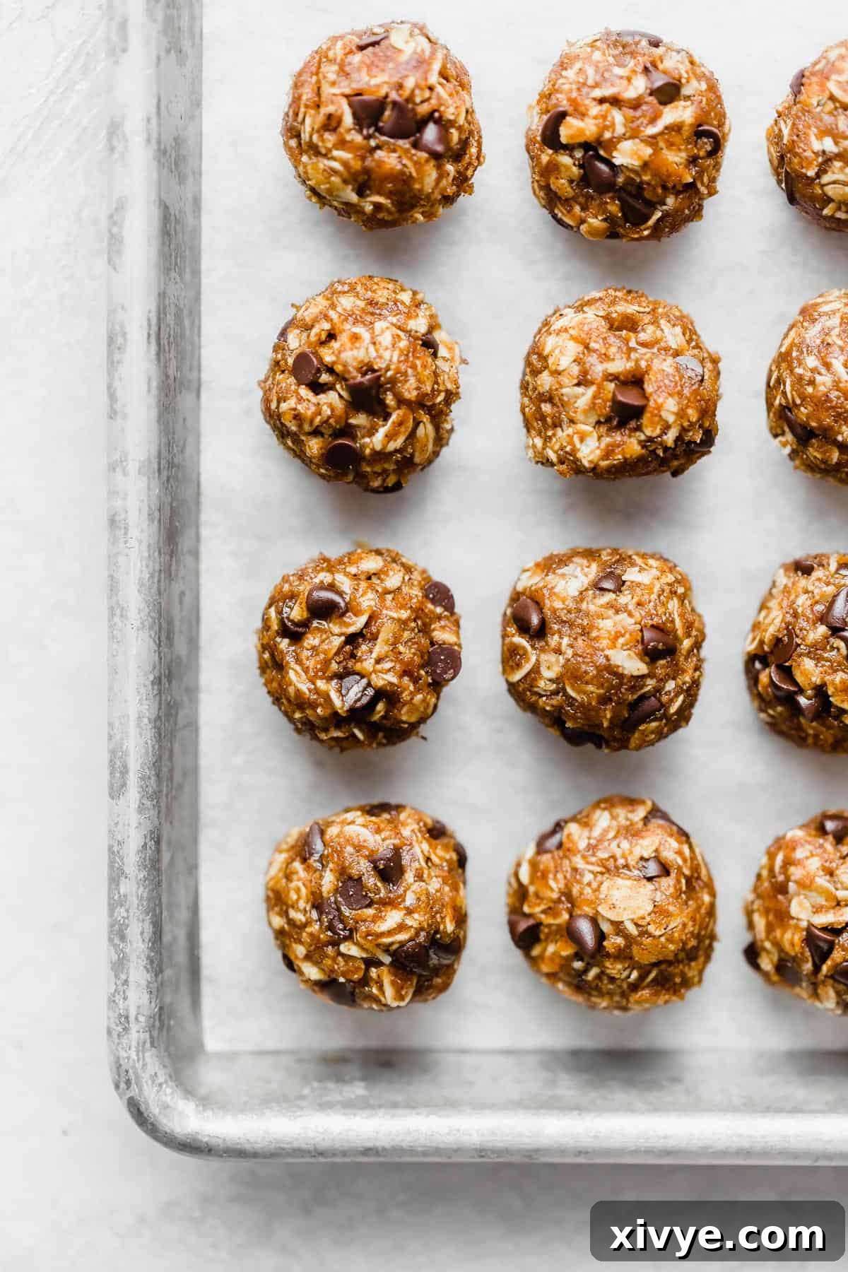 Freshly rolled pumpkin energy balls placed on a parchment-lined baking sheet, ready for chilling.