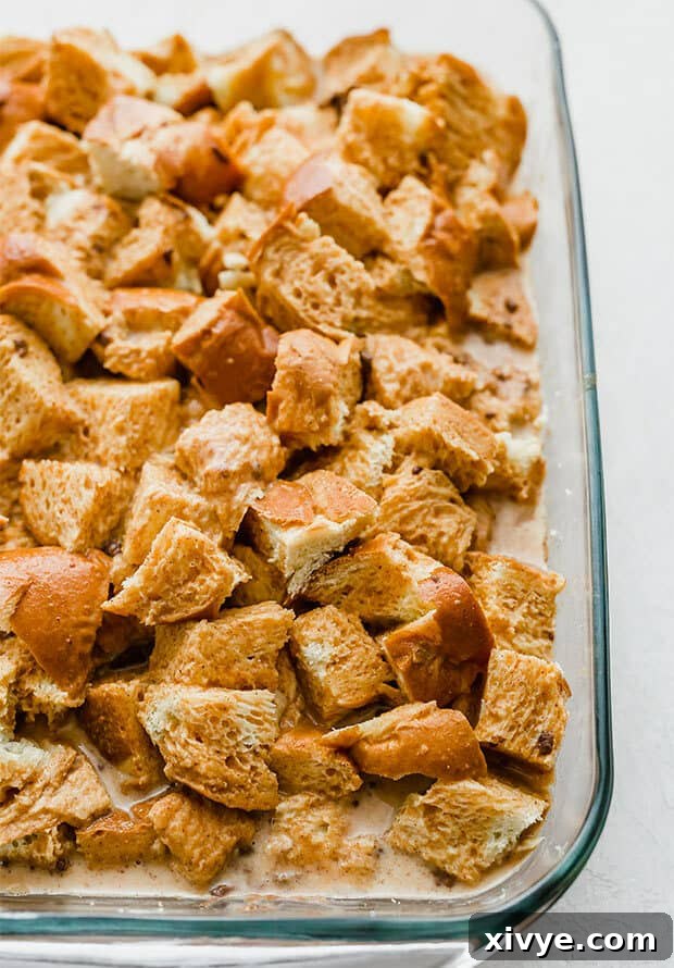 Spiced Pumpkin French Toast Bake 5 A casserole dish filled with cubed challah bread soaking in a rich pumpkin spice egg mixture, ready for chilling.