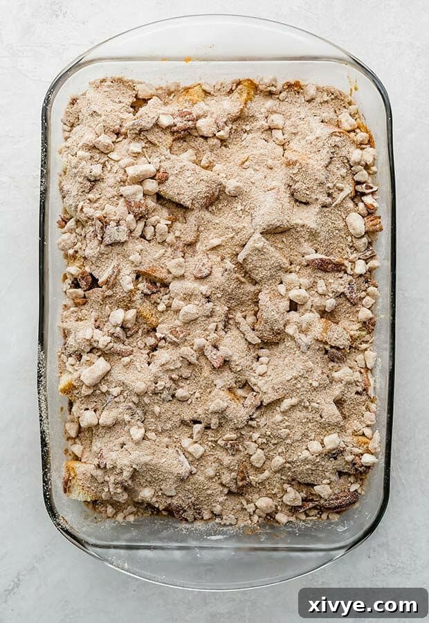 Spiced Pumpkin French Toast Bake 7 An overhead photo of an unbaked Overnight Pumpkin French Toast Casserole, topped generously with pecan streusel.
