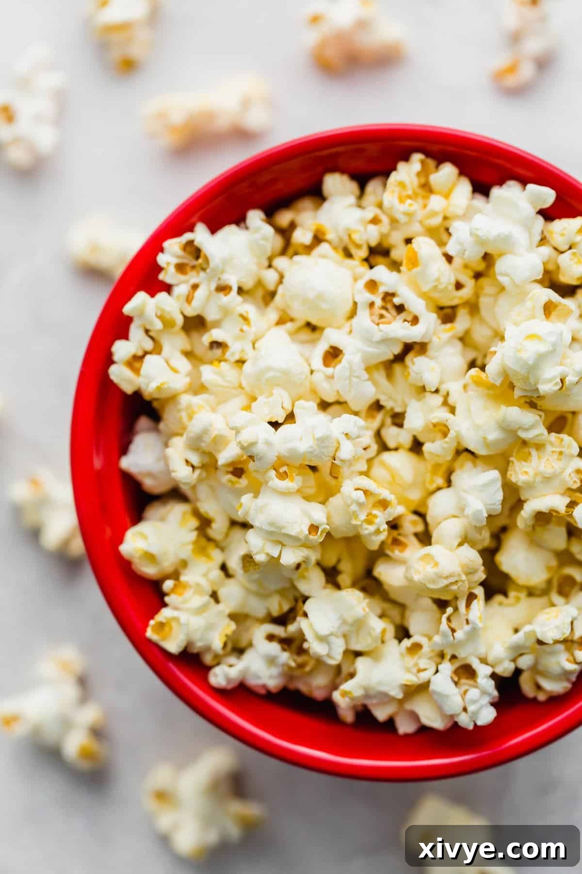 Overhead photo of Movie Theater Popcorn in a vibrant red bowl on a clean white background, showcasing its golden hue and fluffy texture.