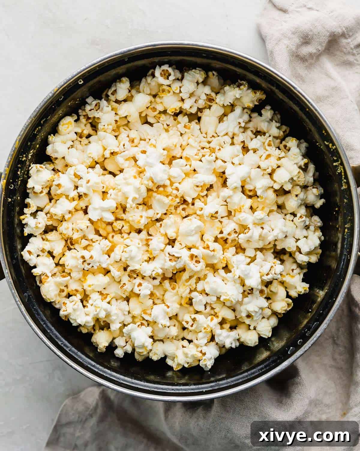 A large black pot filled with freshly made Movie Theater Popcorn, ready to be served. The popcorn is golden and fluffy.