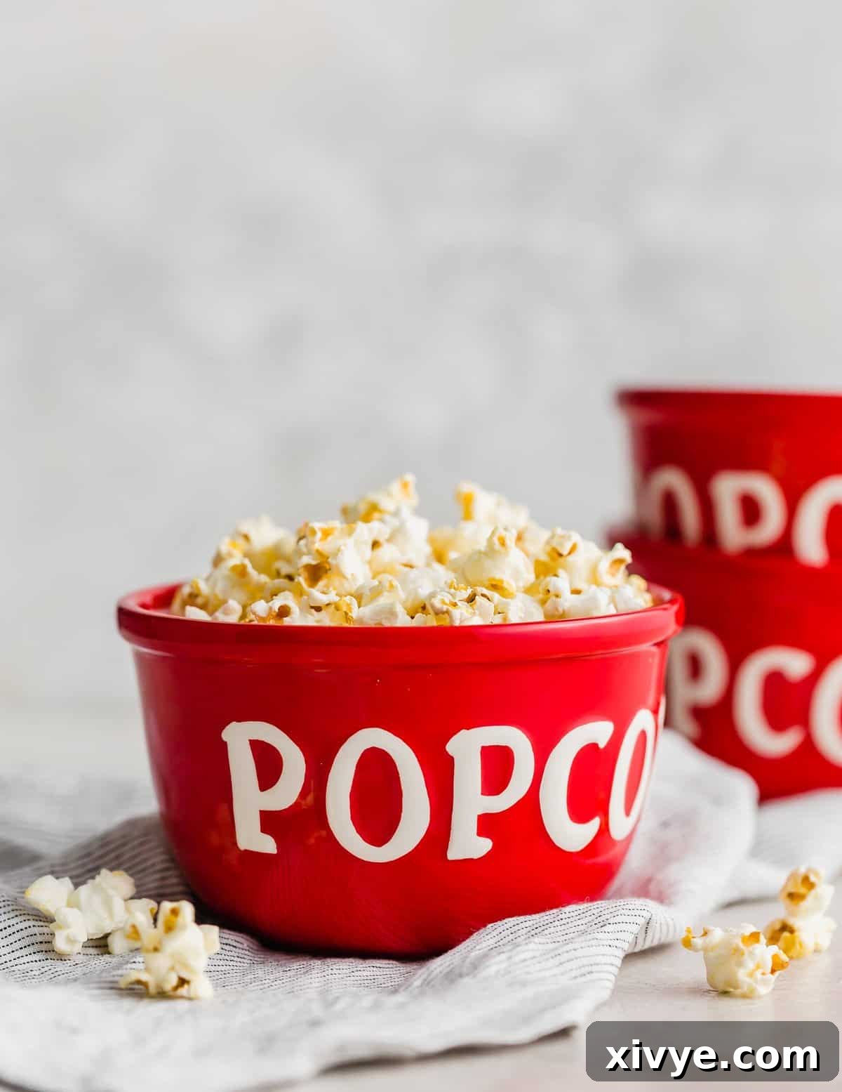 A red bowl with the word "popcorn" emblazoned on its side, filled to the brim with golden, fluffy Movie Theater Popcorn.