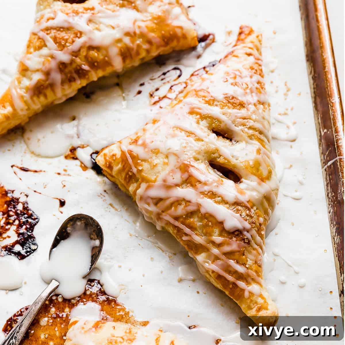 A perfectly glazed Puff Pastry Apple Turnover resting on a sheet of white parchment paper, highlighting its golden crust and inviting appearance.