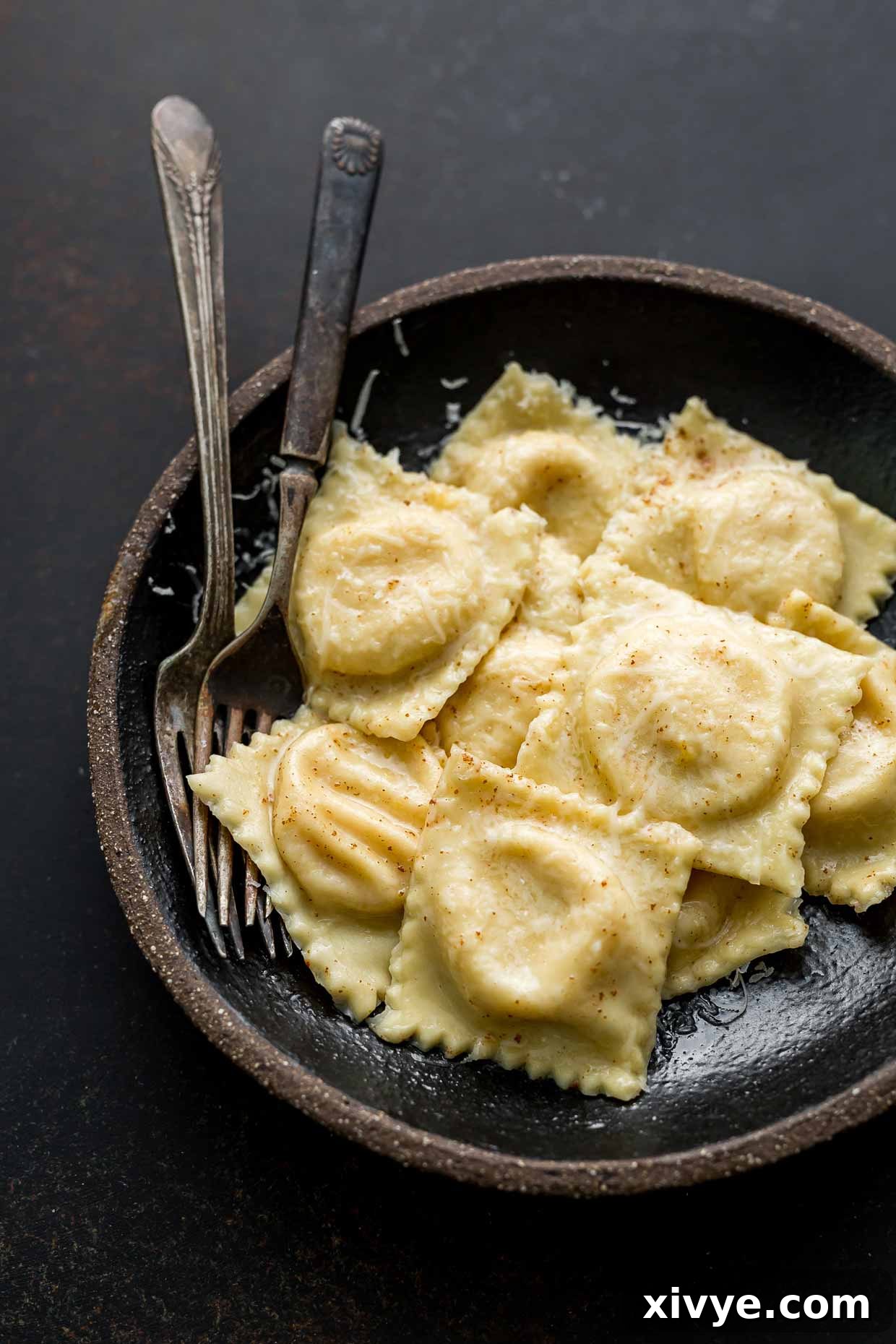 Homemade Butternut Squash Ravioli in a black bowl on a black background. 