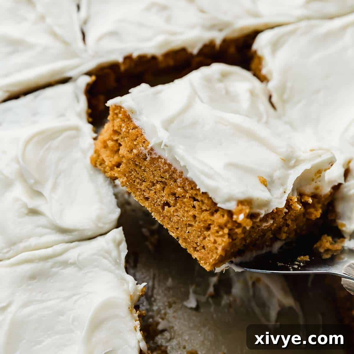 A square slice of Libby's Pumpkin Bars with thick cream cheese frosting, delicately balanced on a metal spatula.