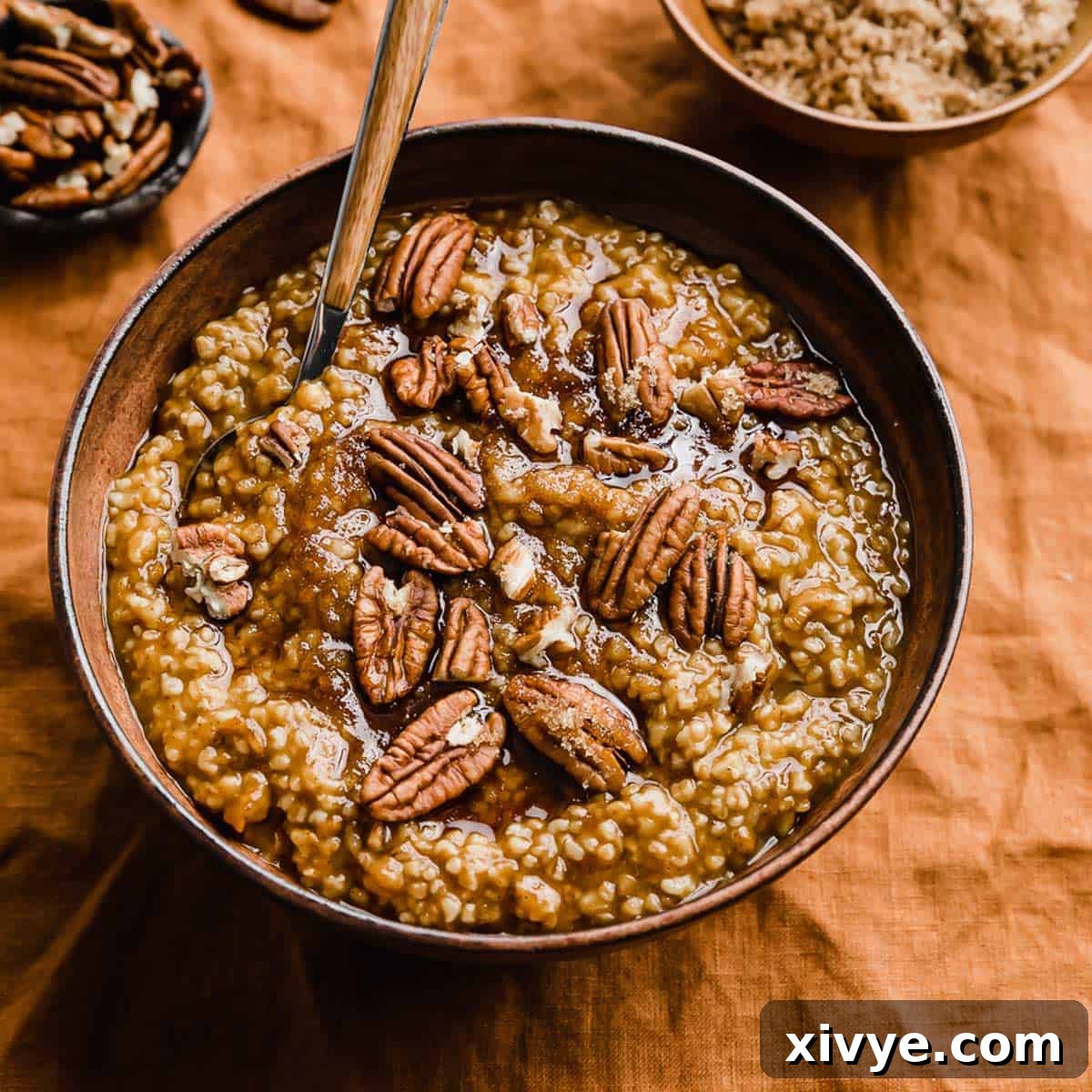 Warm Pumpkin Steel Cut Oats in a rustic brown bowl, generously topped with crunchy pecans and a sprinkle of brown sugar, inviting a cozy breakfast.