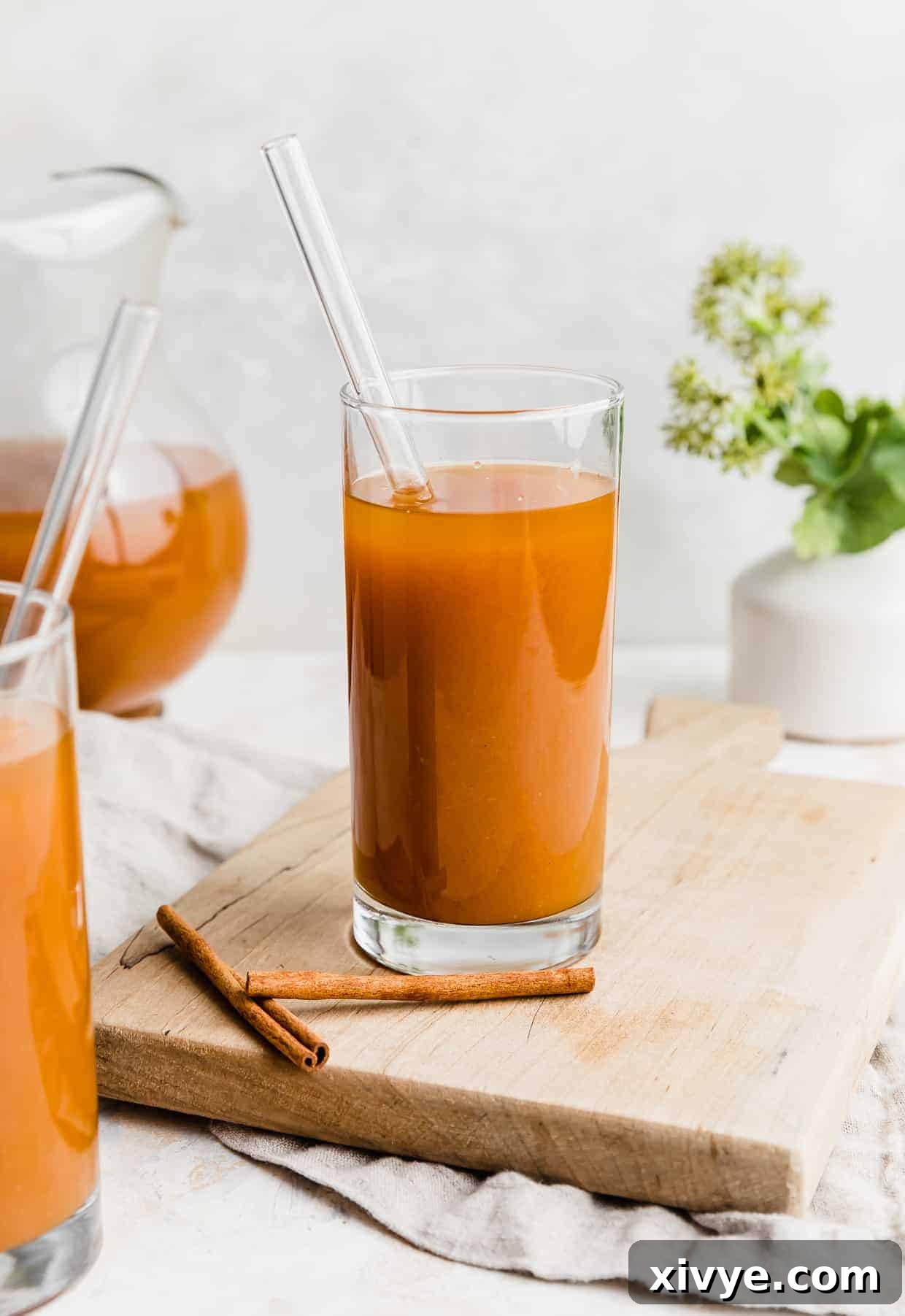 A clear glass full of vibrant orange pumpkin juice against a white background, inviting a magical taste.