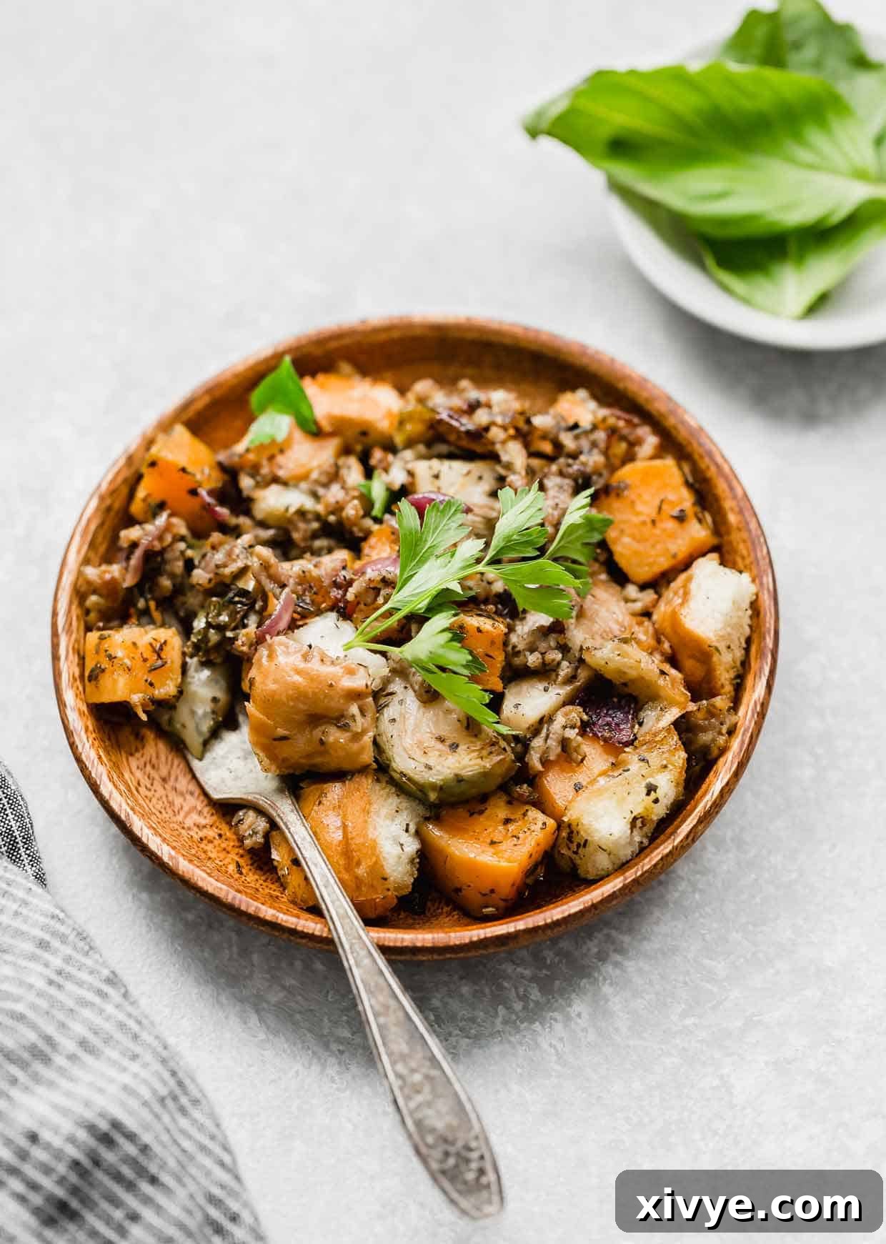 A rustic wooden plate holding a serving of Italian Sausage Stuffing, showcasing its golden-brown crust and visible pieces of sausage and vegetables.