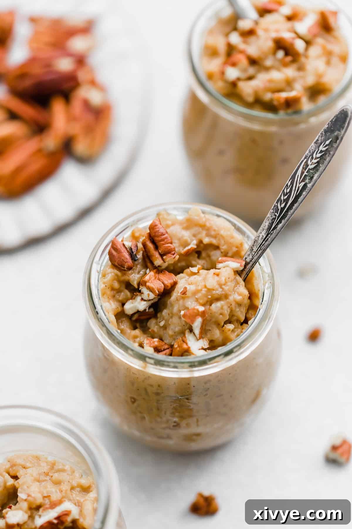 Spiced Pumpkin Rice Pudding 2 Pumpkin Rice Pudding topped with pecans in a glass jar, showcasing its rich, creamy texture and inviting fall colors.