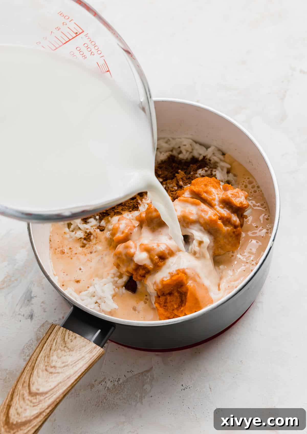 Spiced Pumpkin Rice Pudding 7 Milk being poured into a saucepan with Pumpkin Rice Pudding ingredients in it, creating a rich base.