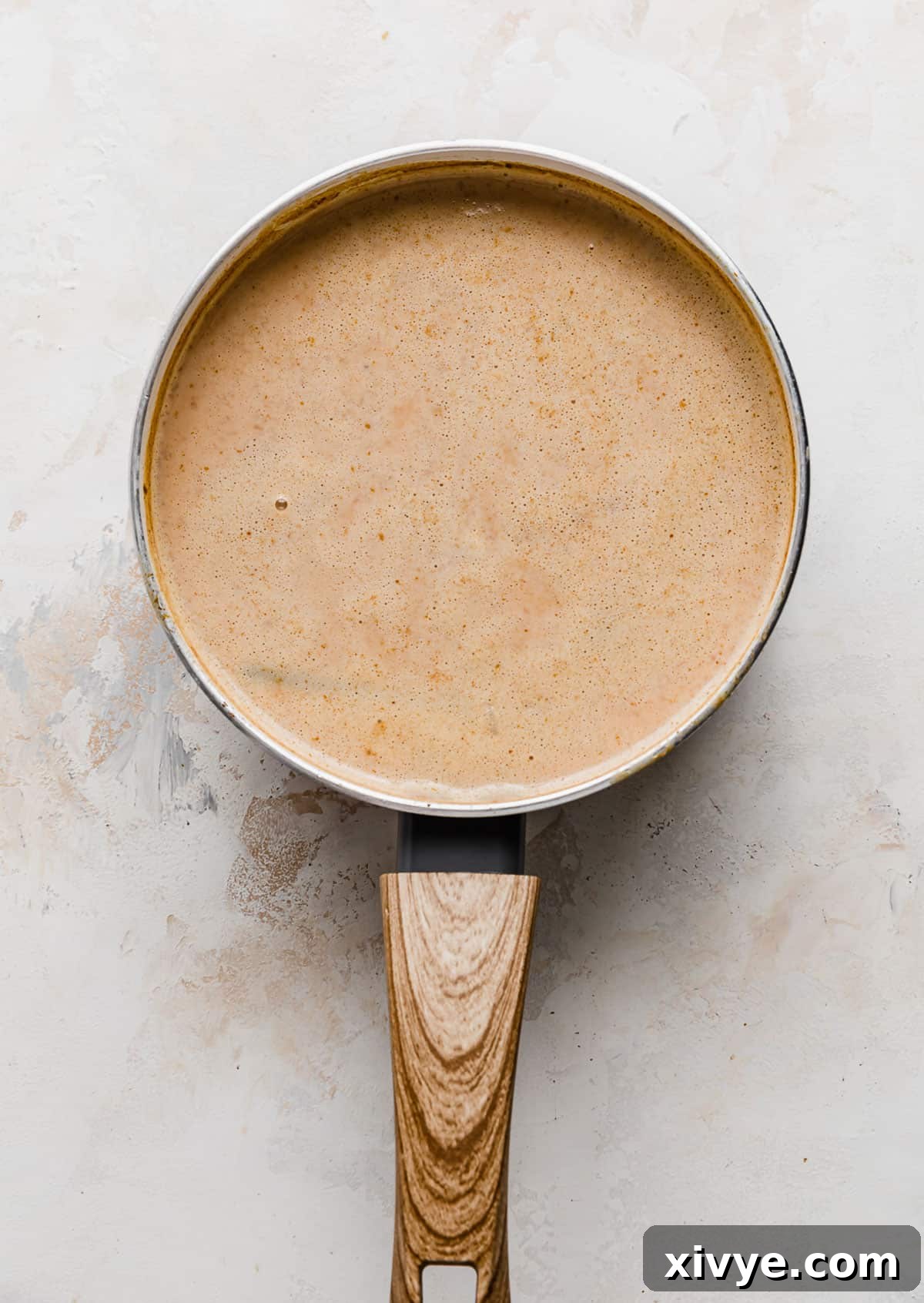 Spiced Pumpkin Rice Pudding 8 A light brown liquid mixture in a saucepan, beginning to thicken into a pudding consistency.