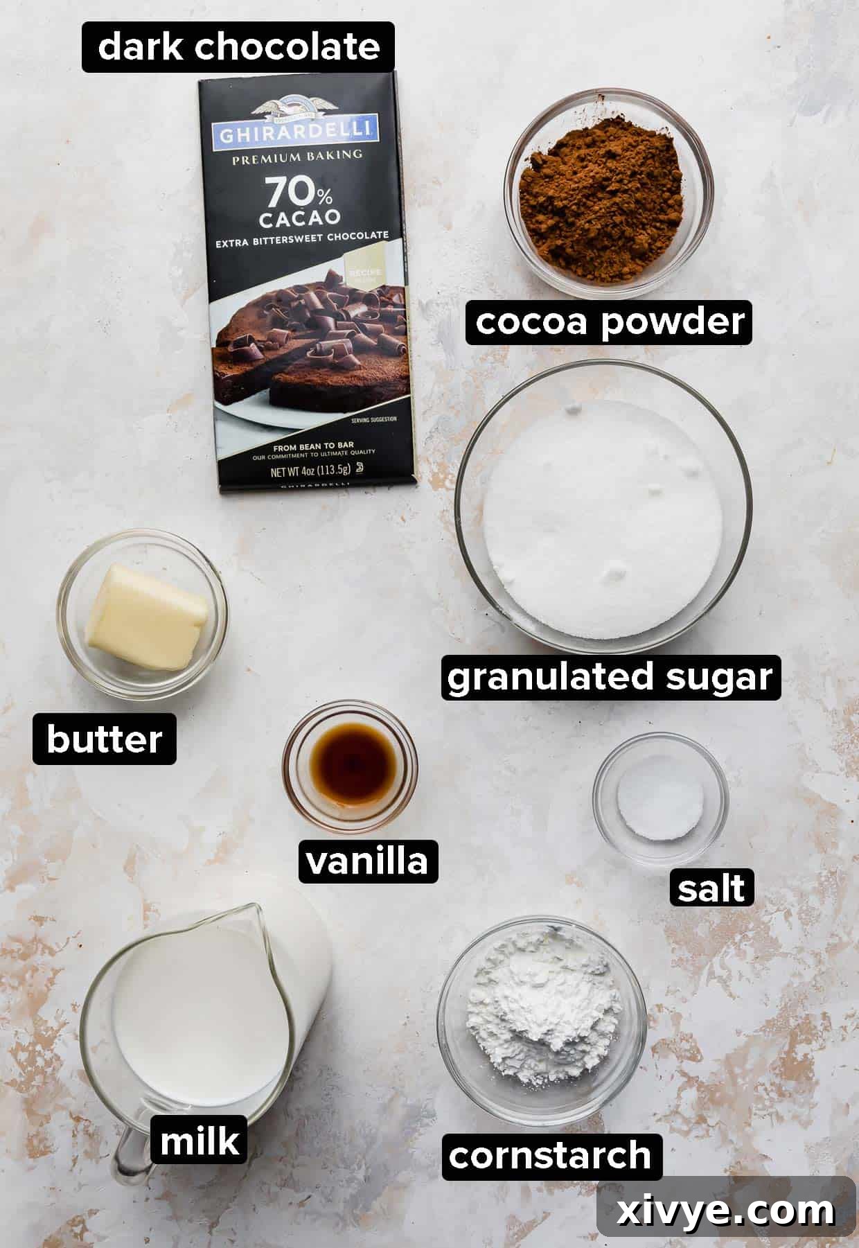 All the essential ingredients for Homemade Chocolate Pudding displayed on a rustic white textured background, ready for preparation.