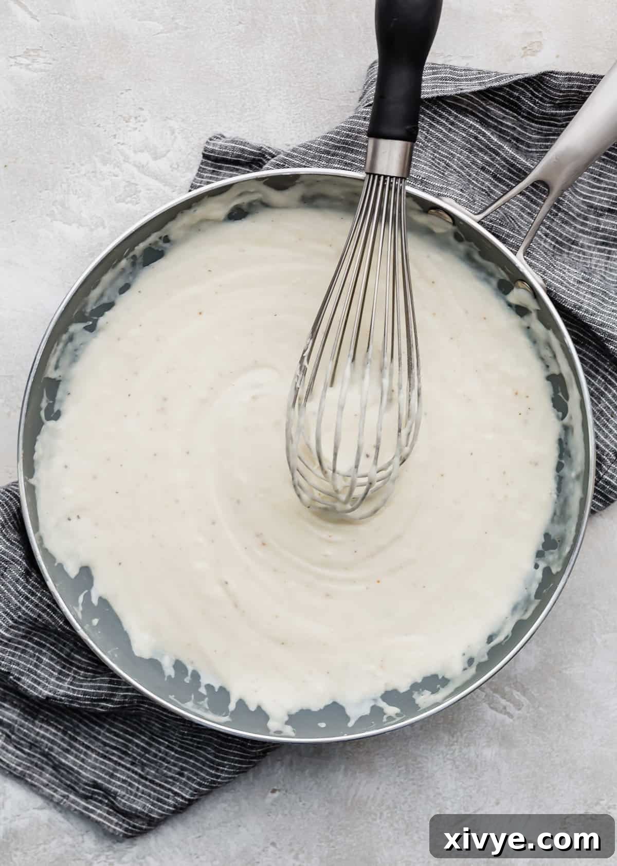 Cauliflower Gratin white sauce made with gruyere cheese in a gray skillet.
