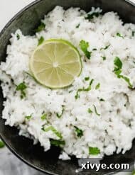 A black bowl filled with Cilantro Lime Rice and garnished with a fresh lime slice.