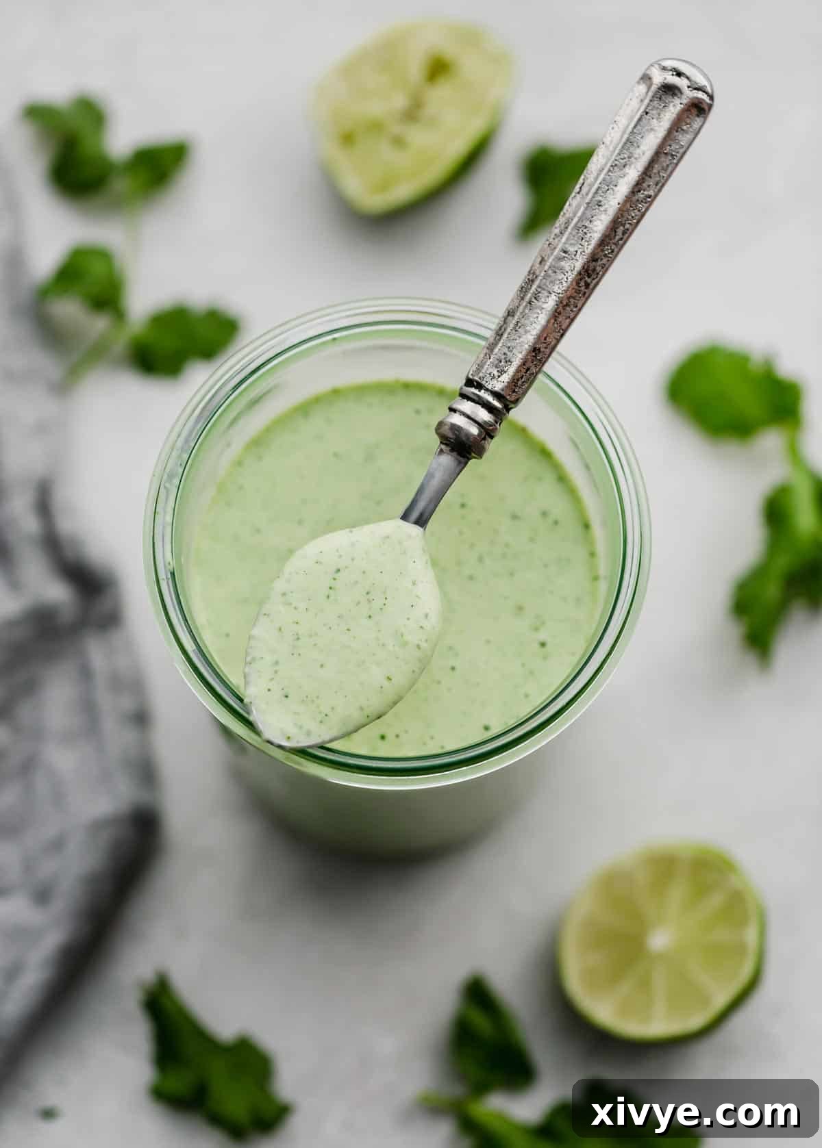 Zesty Cilantro Lime Dressing 2 Cafe Rio Cilantro Lime Dressing in a glass jar with a spoon holding some of the creamy dressing, showcasing its smooth texture and vibrant green color.