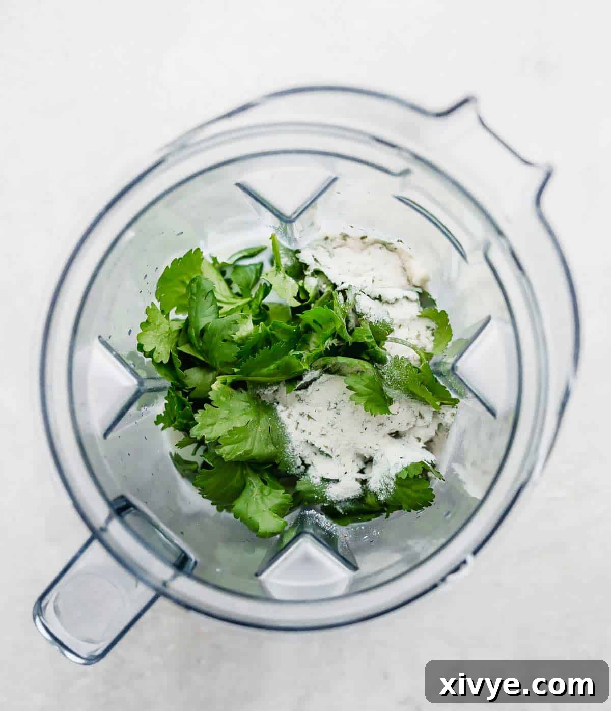 Zesty Cilantro Lime Dressing 4 A blender filled with cilantro, ranch seasoning, jalapeño, lime juice, and tomatillo, ready to be blended into dressing.