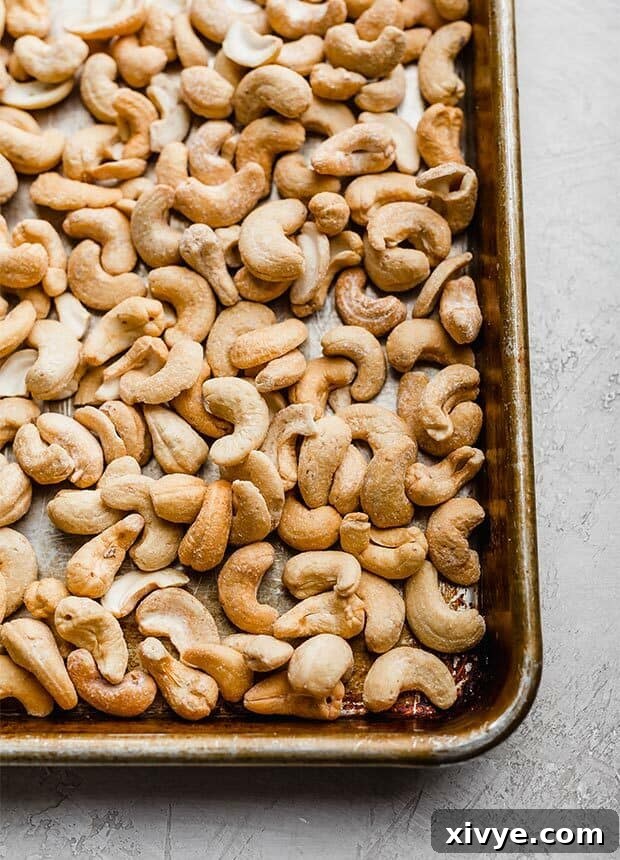 Salted cashews spread evenly on a baking sheet, ready for roasting.