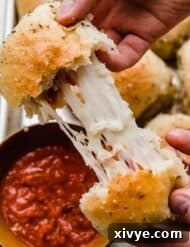 Two hands pulling a pizza roll apart showing the stretchy mozzarella cheese and pepperoni inside.