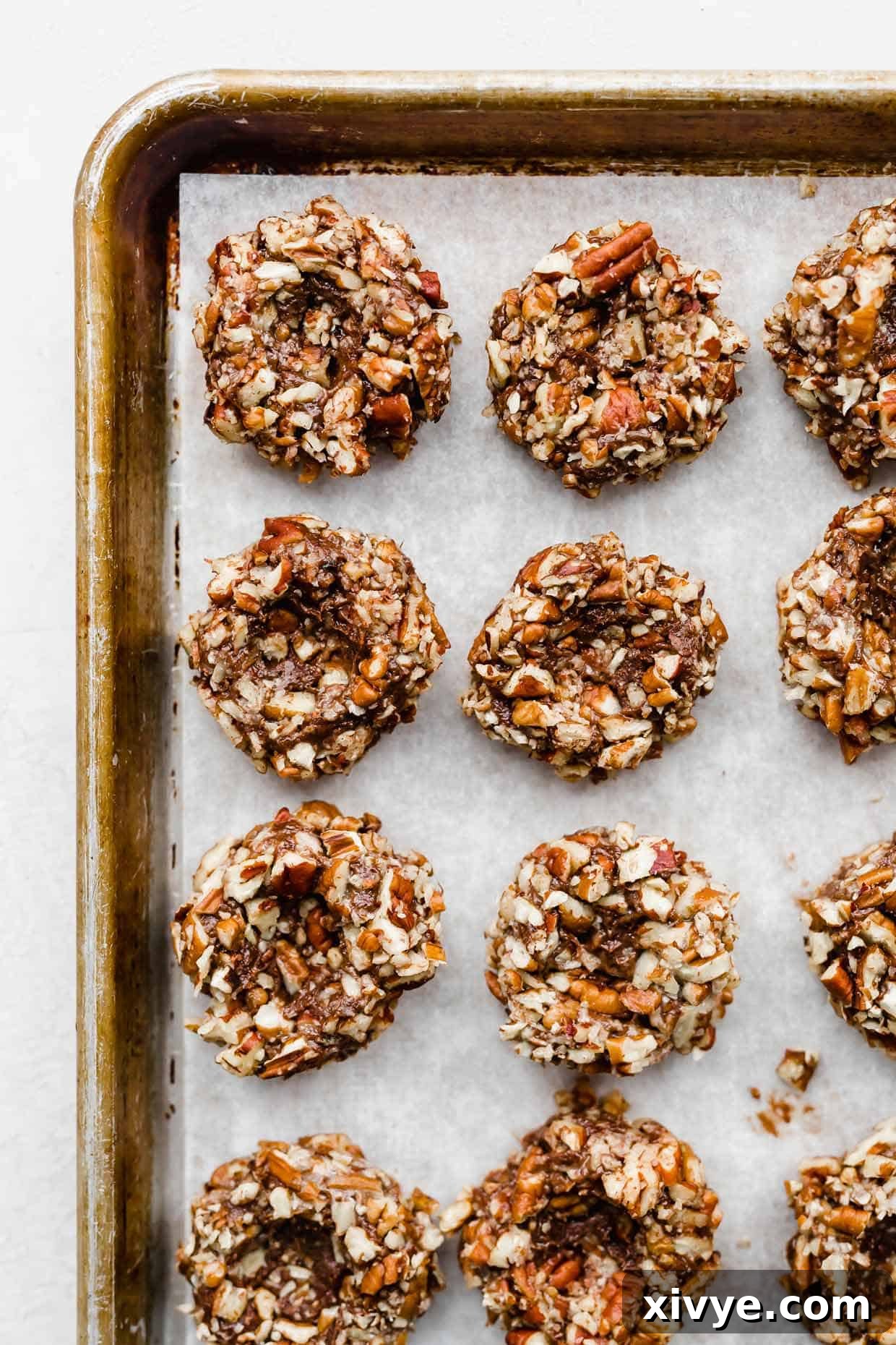 Pecan covered chocolate cookie dough balls with a thumbprint indentation in the center of each ball.