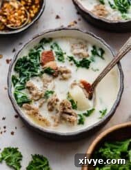 A black bowl with copycat Olive Garden Zuppa Toscana Soup in it and a spoon.