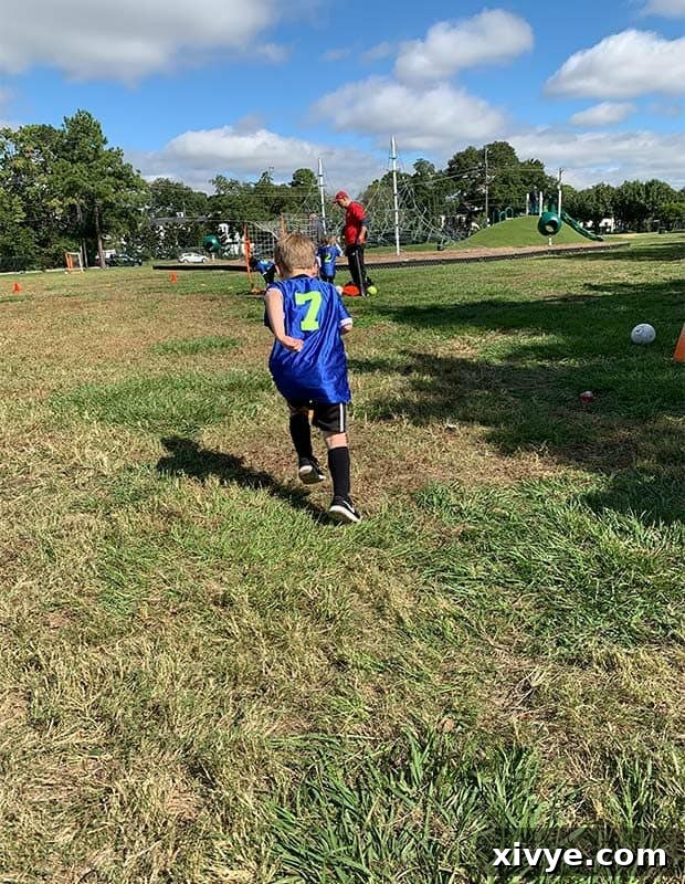 Midweek Sweetness 2 A young boy in a soccer jersey joyfully running across a green field, perhaps chasing a ball or simply enjoying the open space. The image captures motion and youthful exuberance, highlighting a typical family weekend activity.
