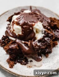 Molten Chocolate Dream 11 Hot fudge cake on a plate topped with ice cream and hot fudge sauce.