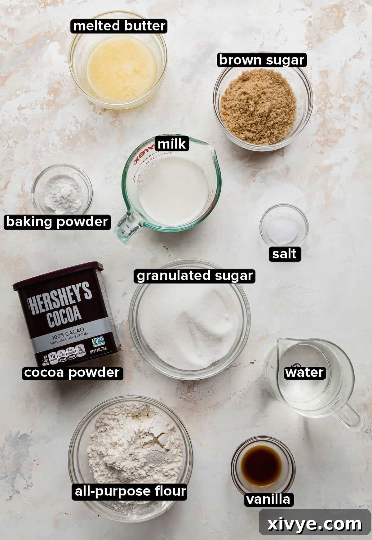 Molten Chocolate Dream 3 Ingredients used to make Hot Fudge Cake portioned into glass bowls on a white and cream textured background.