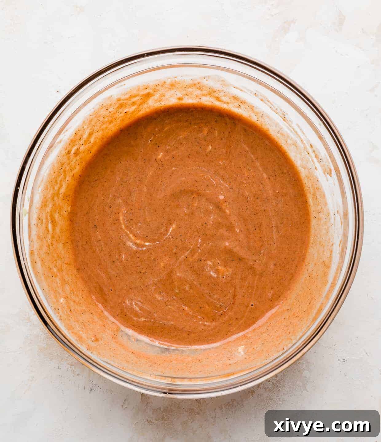 A red/orange colored marinade in a glass bowl.