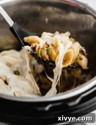 Creamy Instant Pot Philly Cheesesteak Pasta 6 Instant Pot cheesy Philly Cheesesteak Pasta being scooped up from an instant pot.