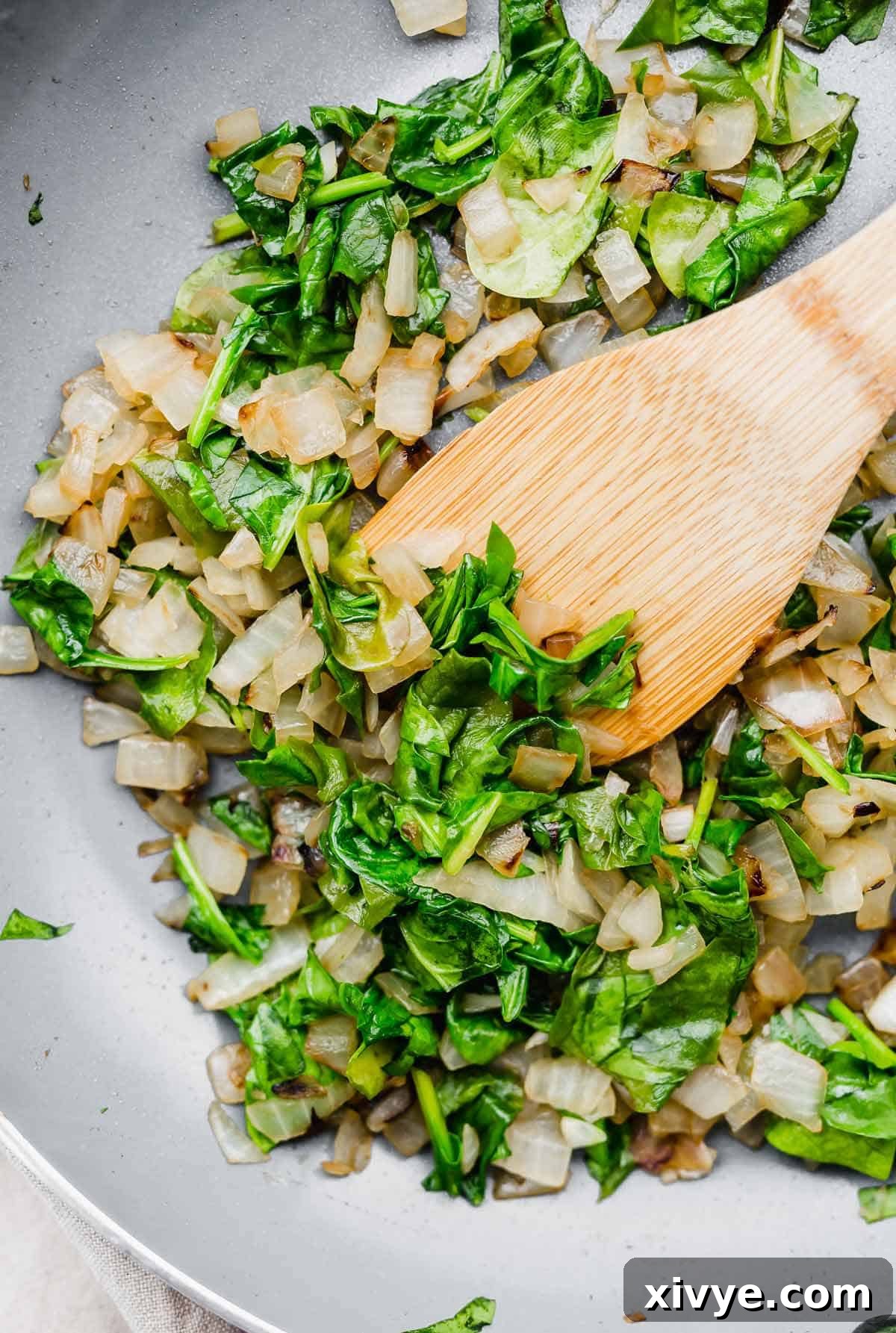 Spinach and onion mixture in a gray skillet.