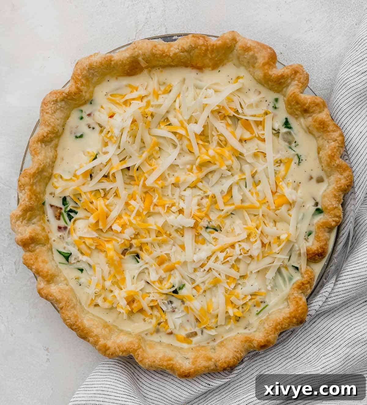 An unbaked Spinach and Bacon Quiche in a homemade pie crust.
