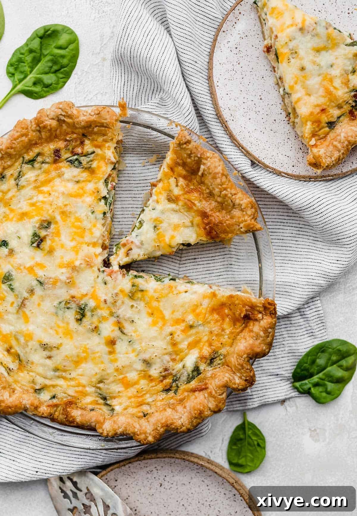 A picture showing a delicious spinach and bacon quiche with a slice cut out.
